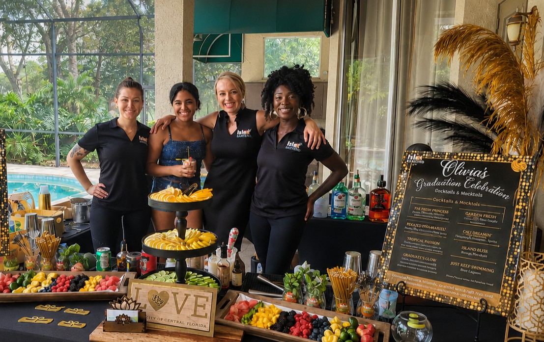 Four ISLE Bartend team members and a graduate beside a graduation celebration cocktail bar
