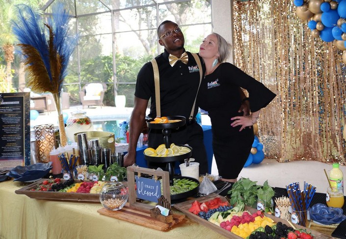 Tony and Mariel posing playfully behind an event bar