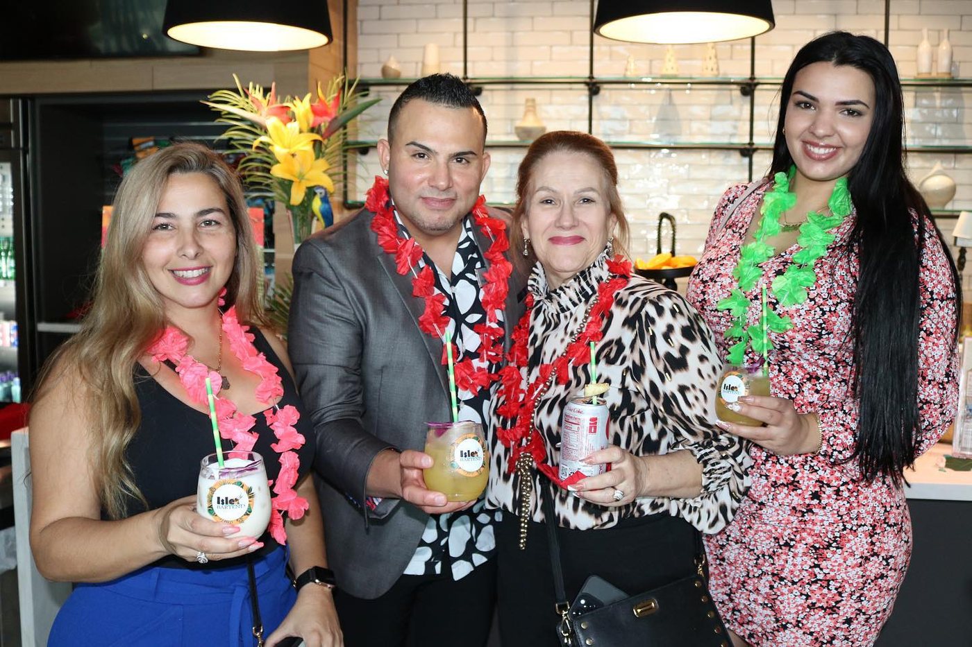 Four guests holding drinks at an ISLE Luau bar